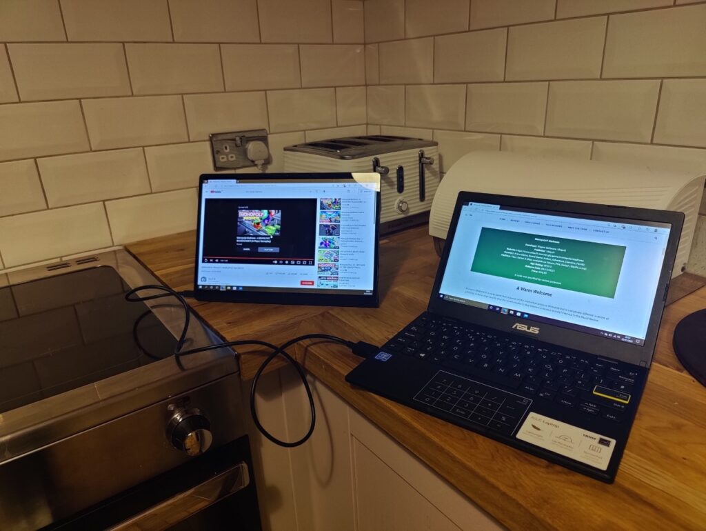 A kitchentop view of a laptop and tablet, a cable plugs them together.