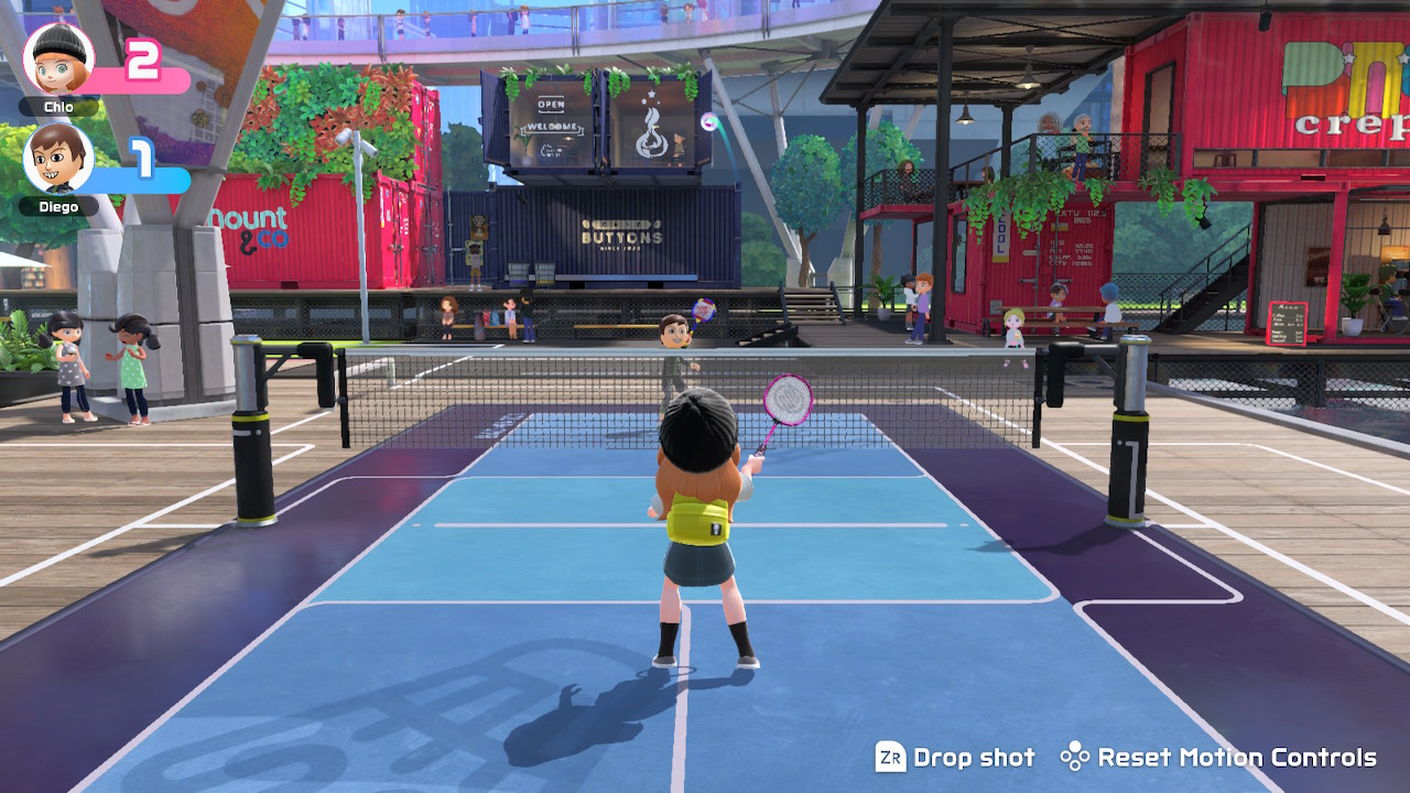 A game of badminton where the shuttlecock is flying high over the net.