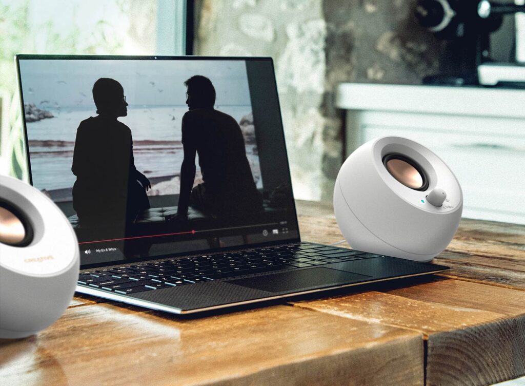 The speakers either side of a laptop playing a video, on a wooden table