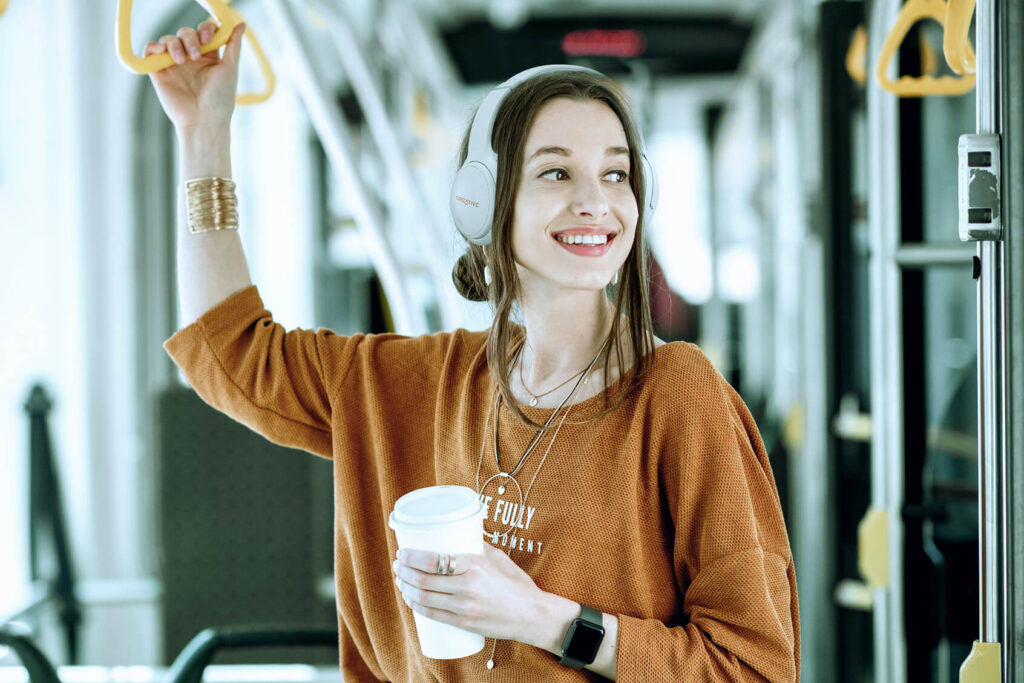 A woman riding a bus carries a coffee cup, wearing the Zen Hybrid