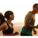 Promotional image of the Cleer ARC wireless earbuds, worn by a female jogger running with a male jogger