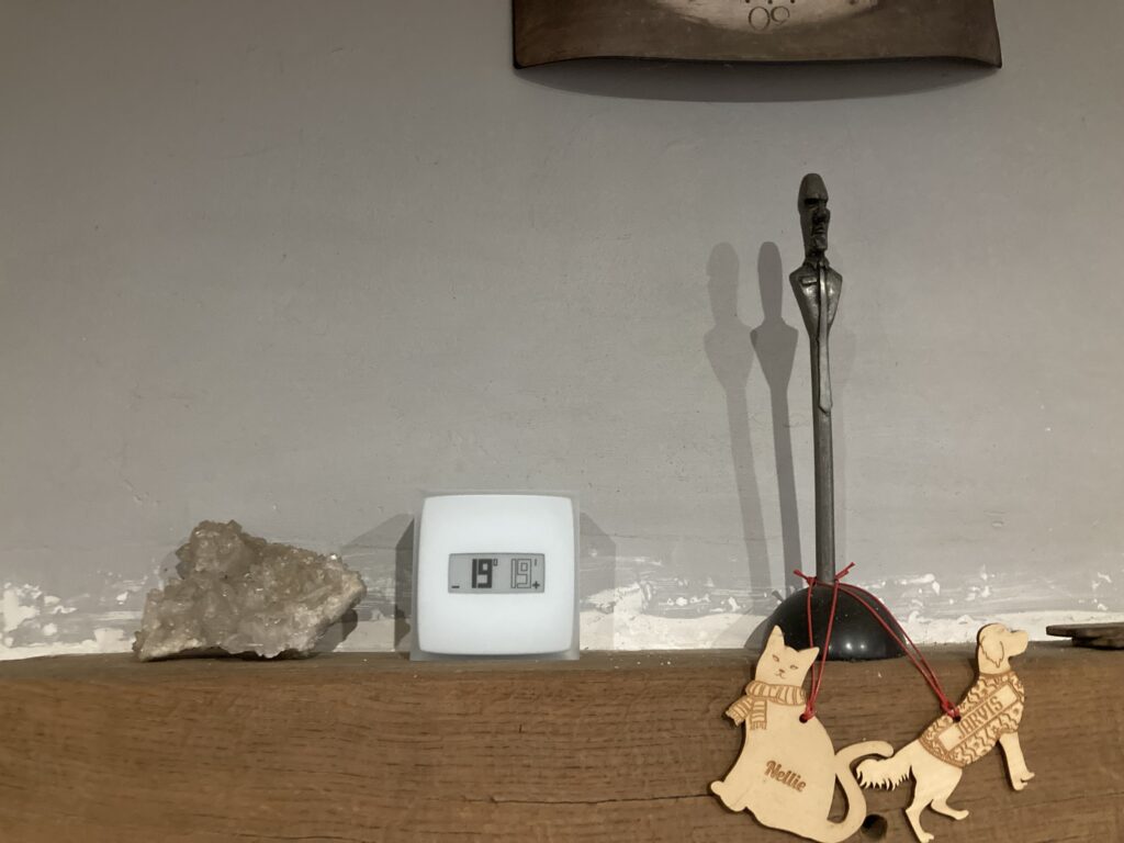 The Smart Thermostat on a shelf next to ornaments