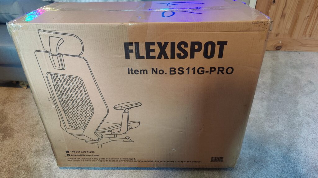 The large cardboard box of the chair has large 'FLEXISPOT' lettering with an illustration of the back of an office chair