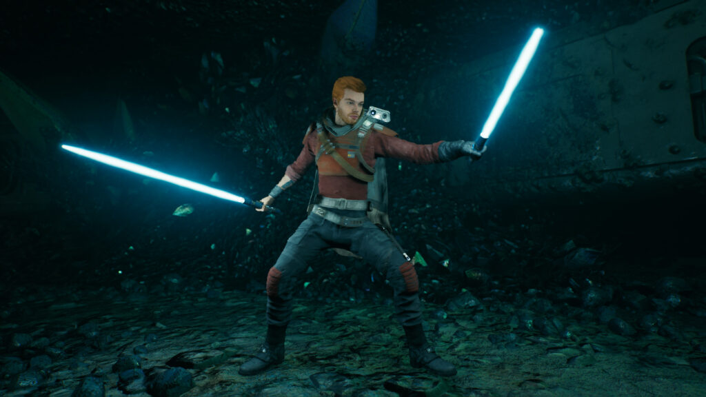 Cal stands in a dark cavern with blue dual lightsabers creating a glow