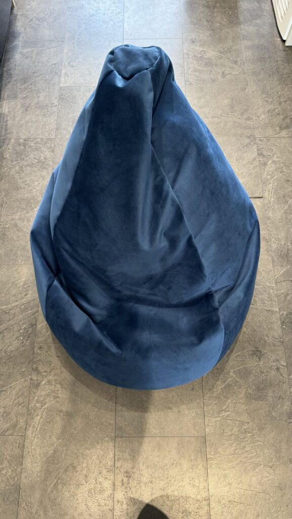 A photograph of the beanbag in a midnight blue colour. It is sat on a linoleum floor.