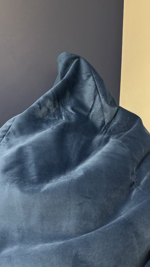 A photograph of the beanbag in midnight blue, after use. It is matched to the colour of the wall behind it.