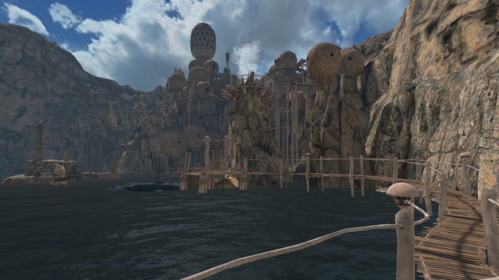 In front of you is a lake body of water surrounded by a wooden walkway. Tall towers made of earthen clay reach to the skyline against the cliffside.