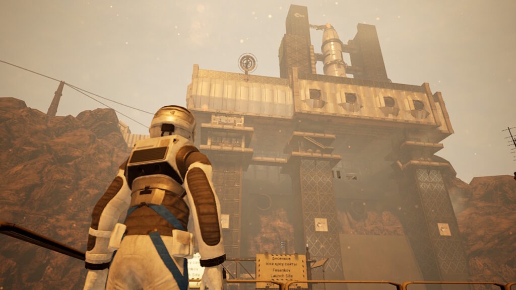 An astronaut stands in the foreground with a rocket ship looming in the background. Around the spacecraft are large pillars of metal holding the station in place.